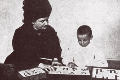 María Montessori con un niño trabajando con letras de lija